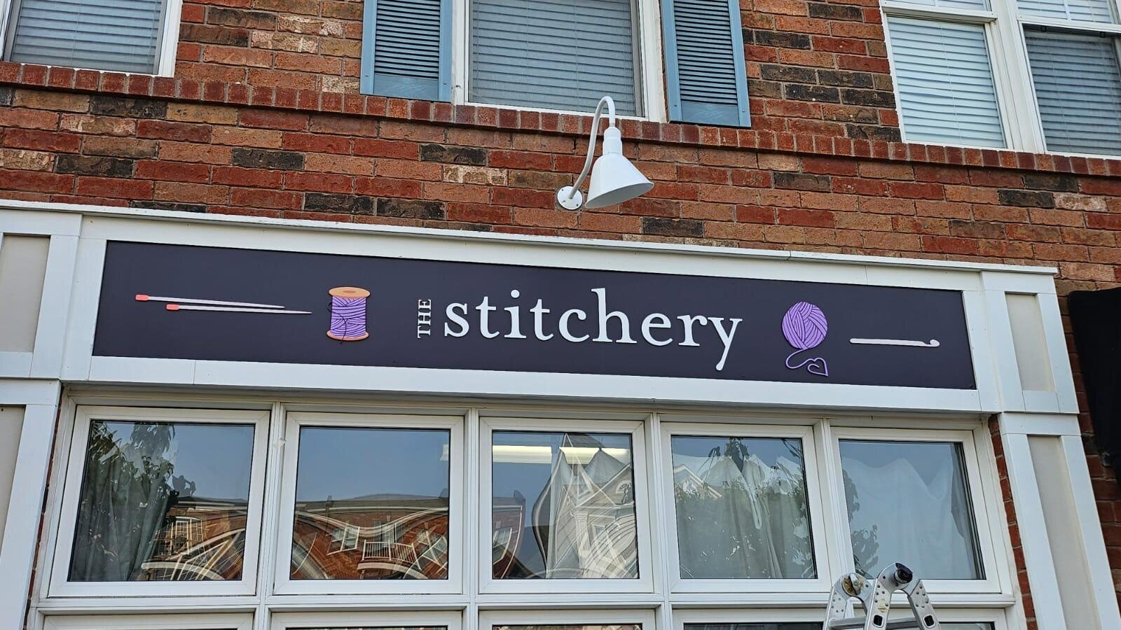The Stitchery illuminated exterior storefront sign on a brick building